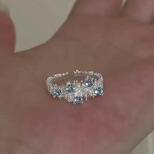 Close-up of irregular silver open ring with five blue zircons on hand display