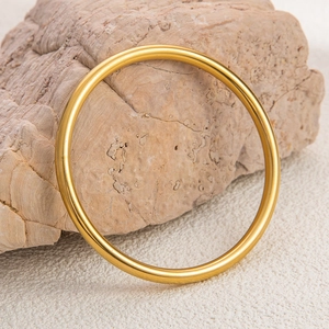 Detailed close-up of a minimalist 18K gold-plated stainless steel circular bangle on rock