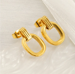 Détail macro de boucles d'oreilles ovales dorées avec accents texturés à rayures