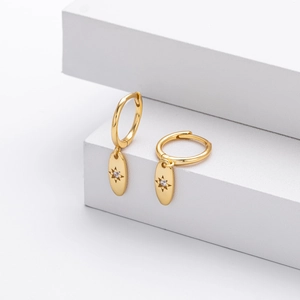 Detail of gold octagon star drop earrings with zircon on minimalist white steps