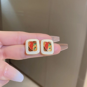 Close-up of vintage square earrings with colorful enamel inlay and golden trim finish