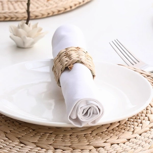 Close-up of handmade woven straw napkin ring on a white napkin over a natural placemat