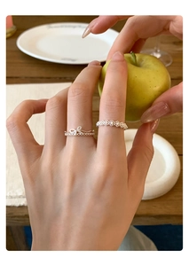 Detail of silver bow and lace cutout rings worn on fingers with a fresh lifestyle look