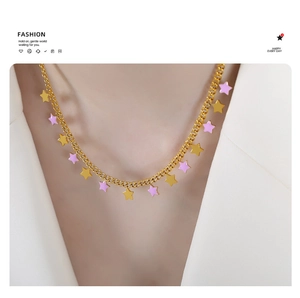 Close-up of a gold necklace with yellow and lavender star pendants worn by a model