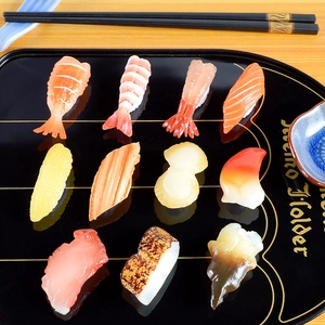 Detailed view of 11 realistic PVC sushi models on a sleek black tray for display