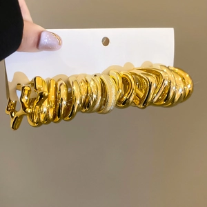 Detailed view of polished gold pleated earrings set on white display card