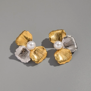 Detailed macro view of two-tone gold and silver flower earrings with white pearl center
