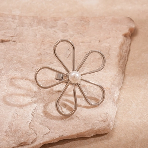 Detail of silver hollow flower ring with white pearl on rustic stone background