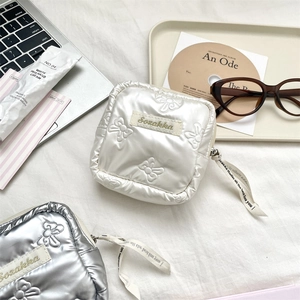 Close-up of quilted bow texture and satin ribbon zipper pull on PU makeup bags