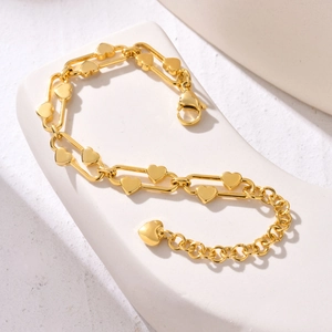 Detailed view of golden heart link bracelet with lobster clasp on white geometric prop
