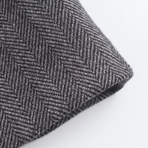 Detailed macro shot of gray herringbone wool fabric texture for wide leg trousers