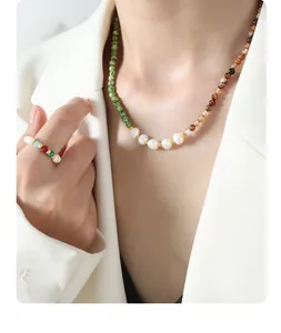 Detail of beaded necklace and ring set with natural pearls and green colorful gemstones