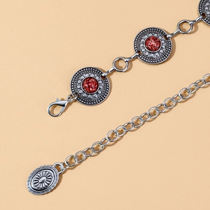 Macro detail of silver bohemian waist chain featuring red stone inlays and lobster clasp