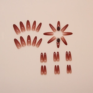 Macro view of long stiletto press-on nails featuring dark red ombré and gemstone accents