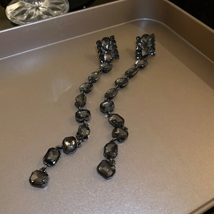 Macro detail of long black crystal tassel earrings on a golden jewelry tray