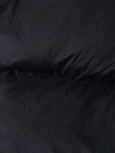 Macro shot of black polyester fabric texture with stitched details on a puffer jacket