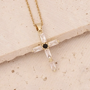 Detailed close-up of 18K gold-plated cross pendant featuring zircons on a stone surface