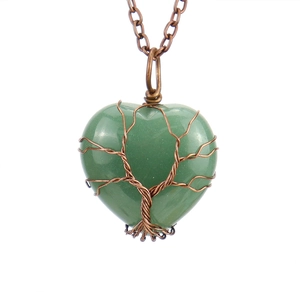 Detailed view of heart-shaped green stone pendant with tree of life wire wrapping