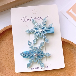 Detail of light blue snowflake hair clips with glitter finish and rhinestone on fabric base