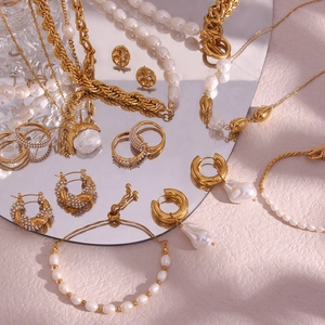 Detail of gold pearl jewelry set including necklace and bracelet on a mirror surface