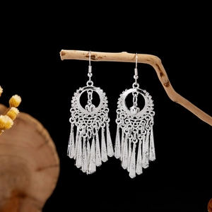 Detail of bohemian silver leaf tassel earrings hanging on a rustic branch background