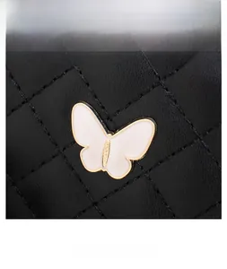 Detail of black quilted leather bag featuring a white butterfly metallic buckle fastener