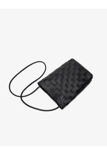 Close-up of premium black woven leather texture on a minimalist bucket crossbody bag