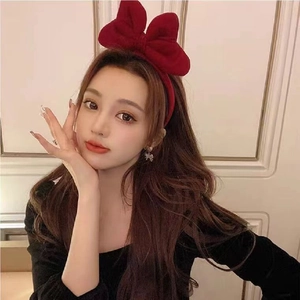 Close-up of a large red velvet bow headband worn by a model for a festive holiday look
