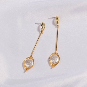 Detail of handmade wire-wrapped white pearl drop earrings with elegant gold plating