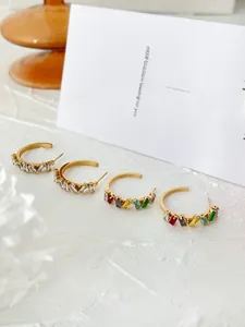 Macro shot of gold-plated C-shape earrings with colorful rectangular zircon stones