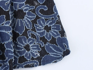 Détail de broderie florale en denim bleu avec bords effilochés sur maille de dentelle noire