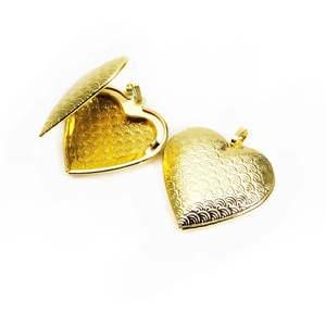 Detailed view of open and closed heart-shaped lockets with gold wavy texture