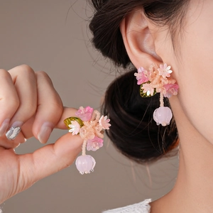 Gros plan sur les boucles d'oreilles fleurs roses perlées avec pétales translucides et argent