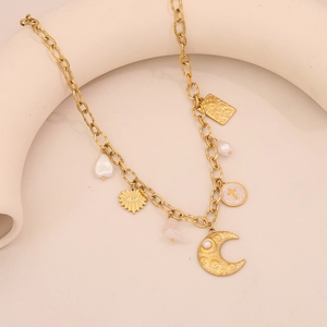 Detail of gold moon necklace with pearls, pink gemstone and celestial charms on a stand
