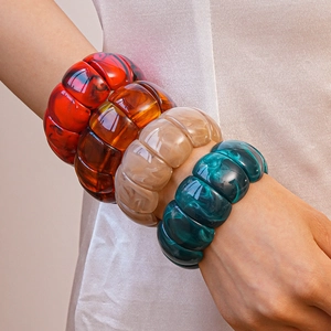 Close-up of wide acrylic stretch bracelets with marble and amber textured patterns