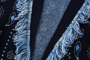 Detail of navy knit cardigan featuring bohemian patterns and delicate fringe trim