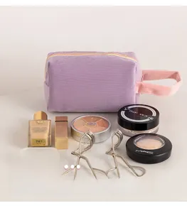 Vista macro della borsa da trucco in velluto viola con manico rosa e cerniera