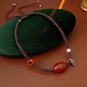 Handmade wax cord necklace featuring red agate and white jade on green velvet