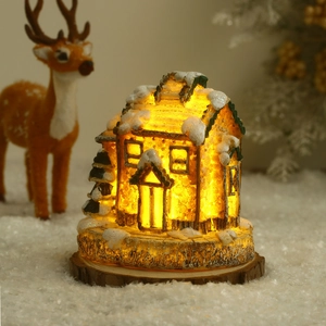 Détail d'une maison de Noël en résine lumineuse avec LED et neige sur socle en bois