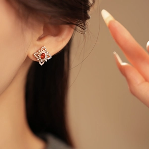 Close-up of model wearing silver flower earrings with red gems and sparkling zircons