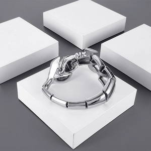 Gros plan d'un bracelet scorpion argenté poli au design mécanique sur un cube blanc