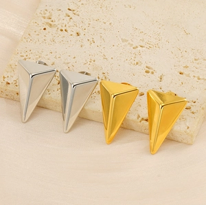 Macro view of geometric triangular 18K gold and silver stud earrings on stone