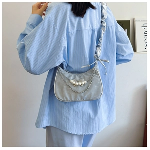 Detail of silver pleated shoulder bag with pearl bow and elegant metal chain tassel
