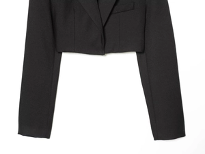 Close-up detail of the black cropped blazer with sharp peak lapels and woven texture