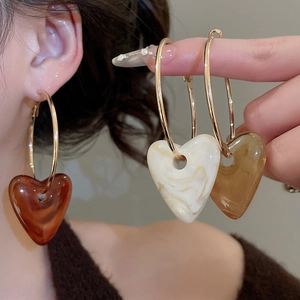 Detail showing acrylic heart pendant earrings in amber and marble white colors