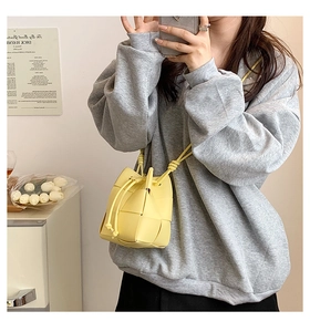 Detail of yellow hand-woven bucket bag with drawstring and thin shoulder strap