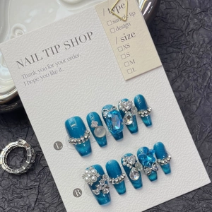 Detailed view of handmade sparkling blue press-on nails with luxury rhinestones and charms