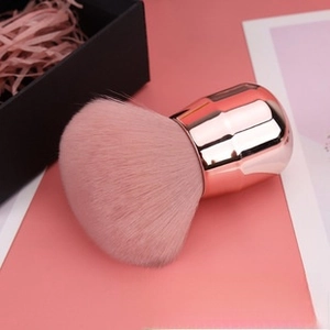 Detail of soft pink synthetic bristles and rose gold metallic handle of a makeup brush