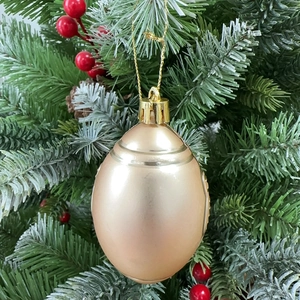 Golden football shaped Christmas ornament with stripes hanging on a festive pine tree branch