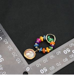 Detail showing colorful beaded hoop earrings with pearl pendant and a metal ruler for scale